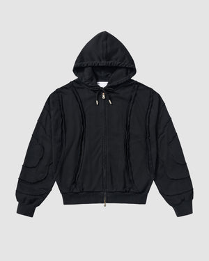 Black Mochi Haze Paneled Hoodie featuring garment washed black cotton with exposed curved seam details throughout body and sleeves, zip-up construction with drawstring hood, ribbed cuffs and hem, relaxed oversized fit silhouette, flat lay product shot on light background.