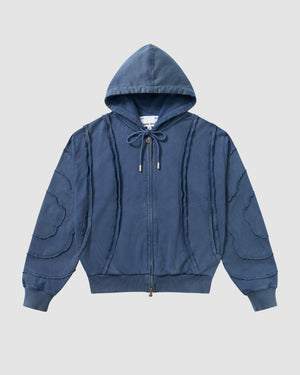 Indigo Mochi Haze Paneled Hoodie featuring garment washed indigo cotton with exposed curved seam details throughout, zip-up construction with drawstring hood, ribbed cuffs and hem, relaxed oversized fit silhouette, flat lay product shot on light background.