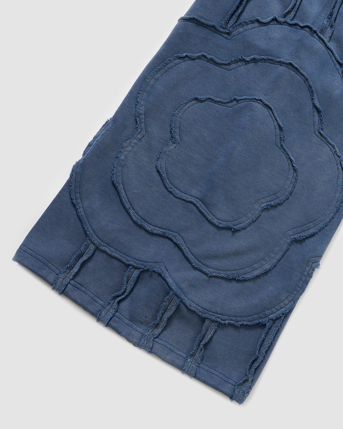 Indigo Mochi Haze Paneled Sweatpants full leg detail showing exposed curved seam construction throughout length, relaxed wide-leg fit with distressed finishing, garment washed indigo cotton fabric, photographed on light background.