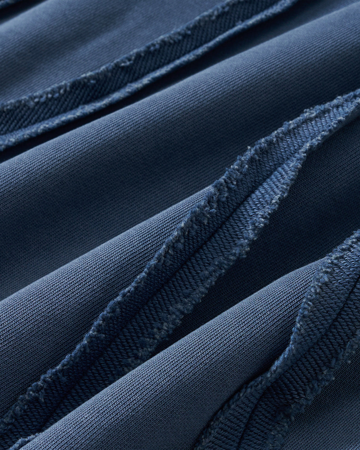 Indigo Mochi Haze Paneled Sweatpants fabric texture detail showing garment washed indigo cotton material with exposed seam construction and distressed finishing, close-up macro shot.