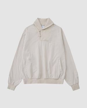 The IVORY SHAWL COLLAR ANORAK by Sundae School features long sleeves, a high collar, button details, front pockets, and elastic cuffs and hem. Made from a cotton-nylon shell in light beige and shown on a plain white background.