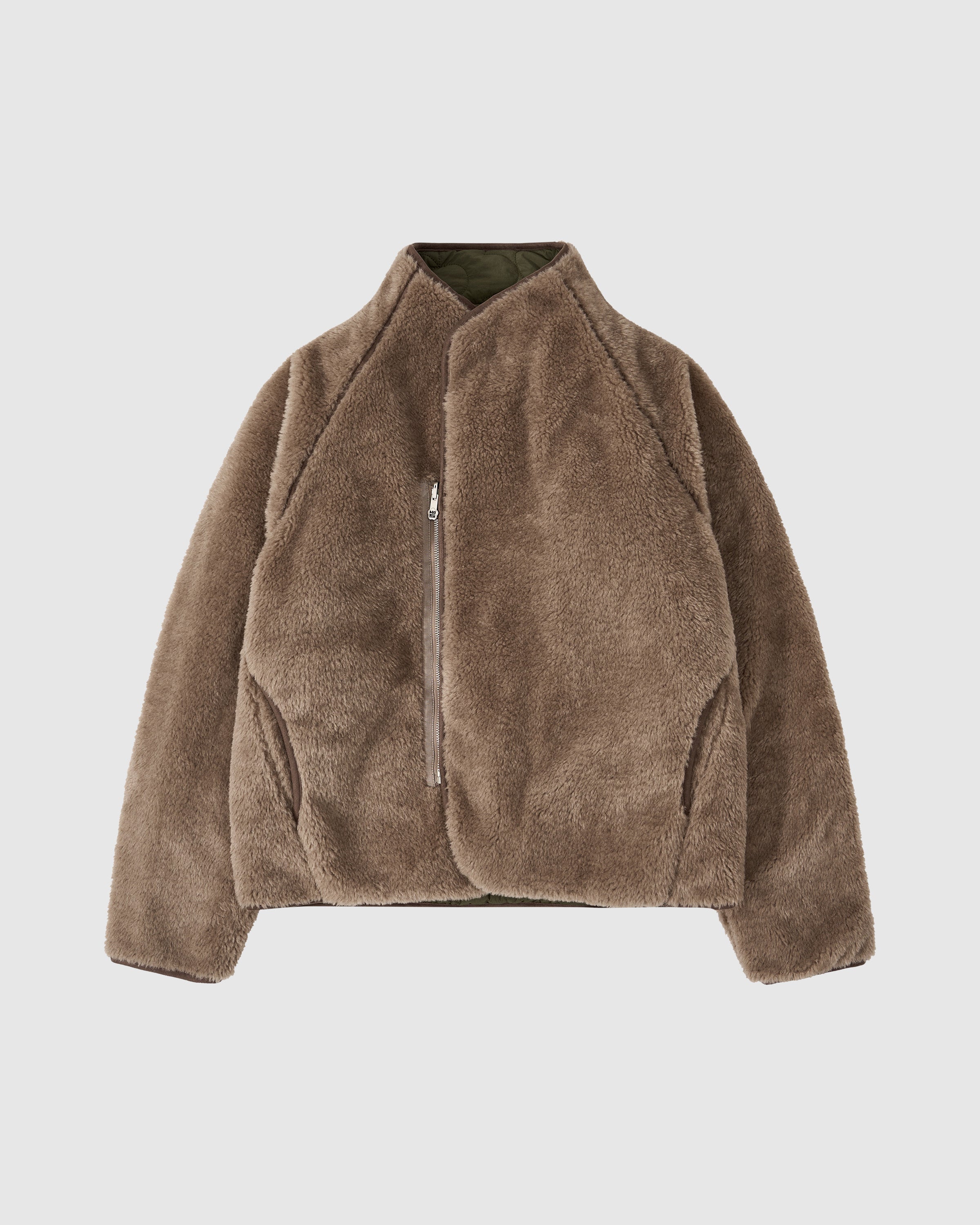 The Sundae School REVERSIBLE FLOWER QUILTED JEOGORI FLEECE is shown on a plain white background, featuring a brown sherpa material, high collar, and asymmetrical front zipper.
