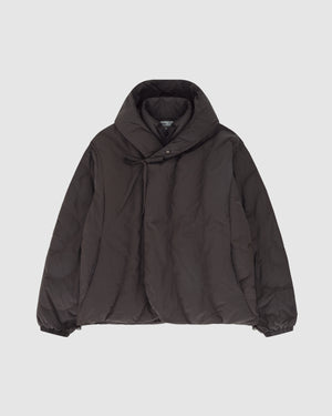 The CHARCOAL HEAVYWEIGHT MOCHI PUFFER by Sundae School, a dark brown winter jacket with a high collar, diagonal button closure, and elastic cuffs, is laid flat on a plain light gray background.