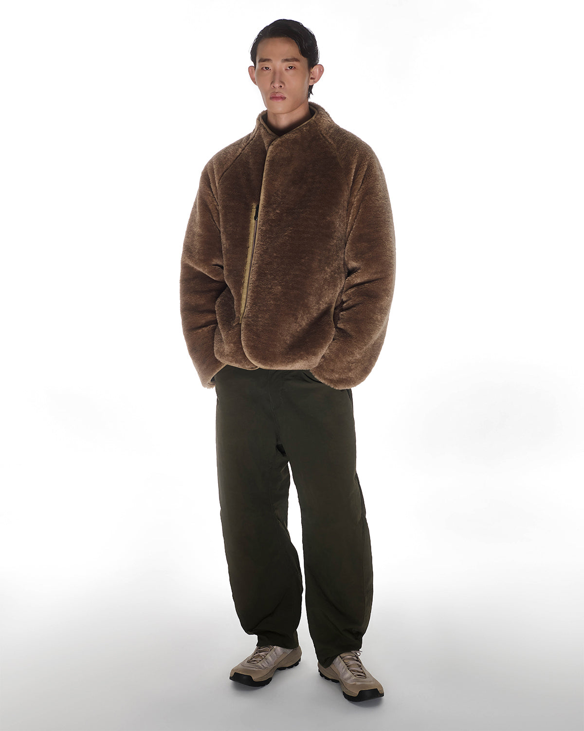 A person stands facing forward in the [PRE-ORDER] REVERSIBLE FLOWER QUILTED JEOGORI FLEECE by Sundae School, paired with dark olive pants and light sneakers against a plain white background.