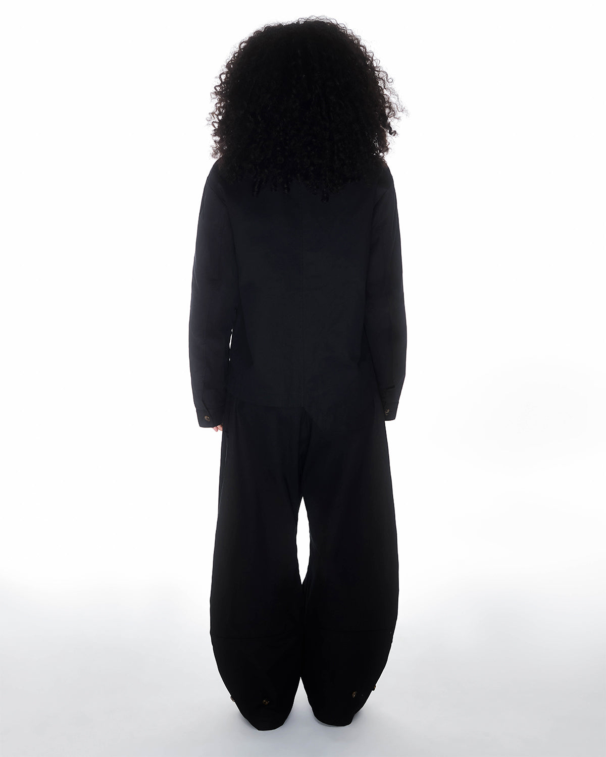 A person with curly hair faces away from the camera, wearing the BLACK HANBOK TIE BLAZER by Sundae School against a white background.