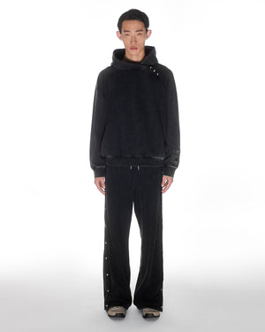 Black garment washed cotton Fade Black Hanbok Hoodie with custom dome snap details on hood paired with matching black Fade Black Snap Sweatpants featuring dome snaps down side seams, pullover hoodie construction, relaxed oversized fit silhouette, modeled on light background, shown in front view.