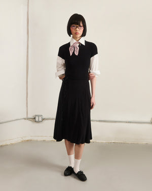 A person with short dark hair and glasses stands in a plain room, wearing the CINDY POLO DRESS from Sundae School. They look directly at the camera.