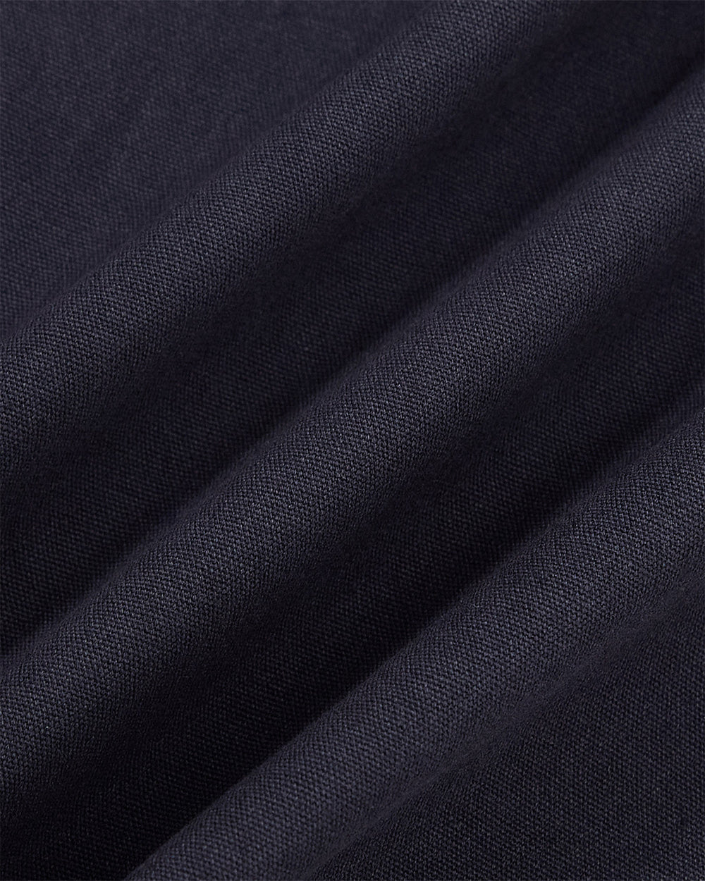 Close-up of the NAVY HANBOK TIE BLAZER by Sundae School, featuring dark navy blue 100% cotton fabric with visible weaving, diagonal folds, and a smooth finish—ideal for its distinctive side tie closure.