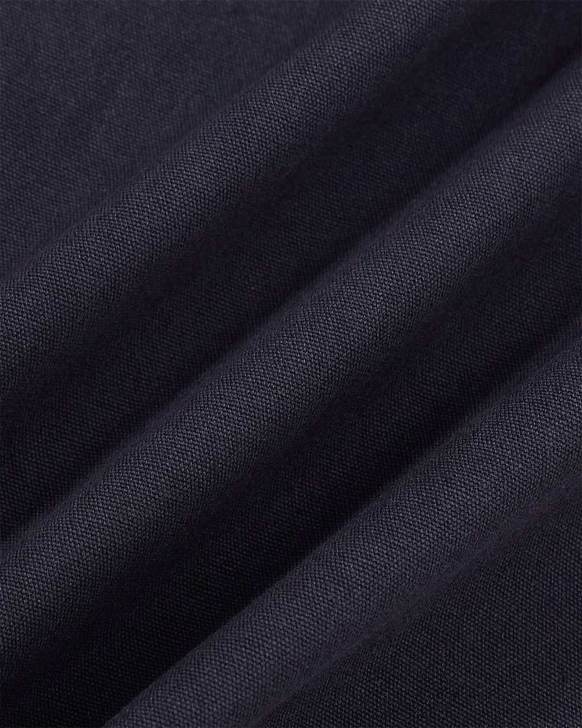 Close-up of the NAVY HANBOK TIE BLAZER by Sundae School, featuring dark navy blue 100% cotton fabric with visible weaving, diagonal folds, and a smooth finish—ideal for its distinctive side tie closure.