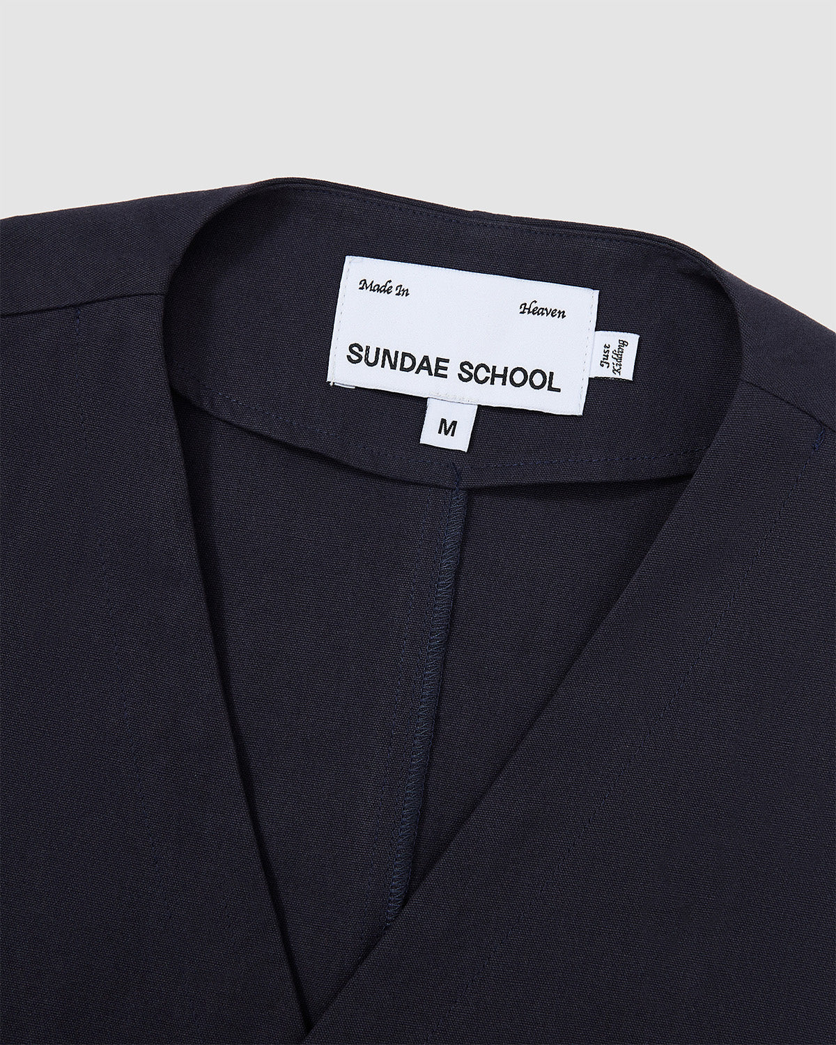 Close-up of the collar area of the Hanbok Tie Blazer showing the Sundae School brand label and V-neckline construction.