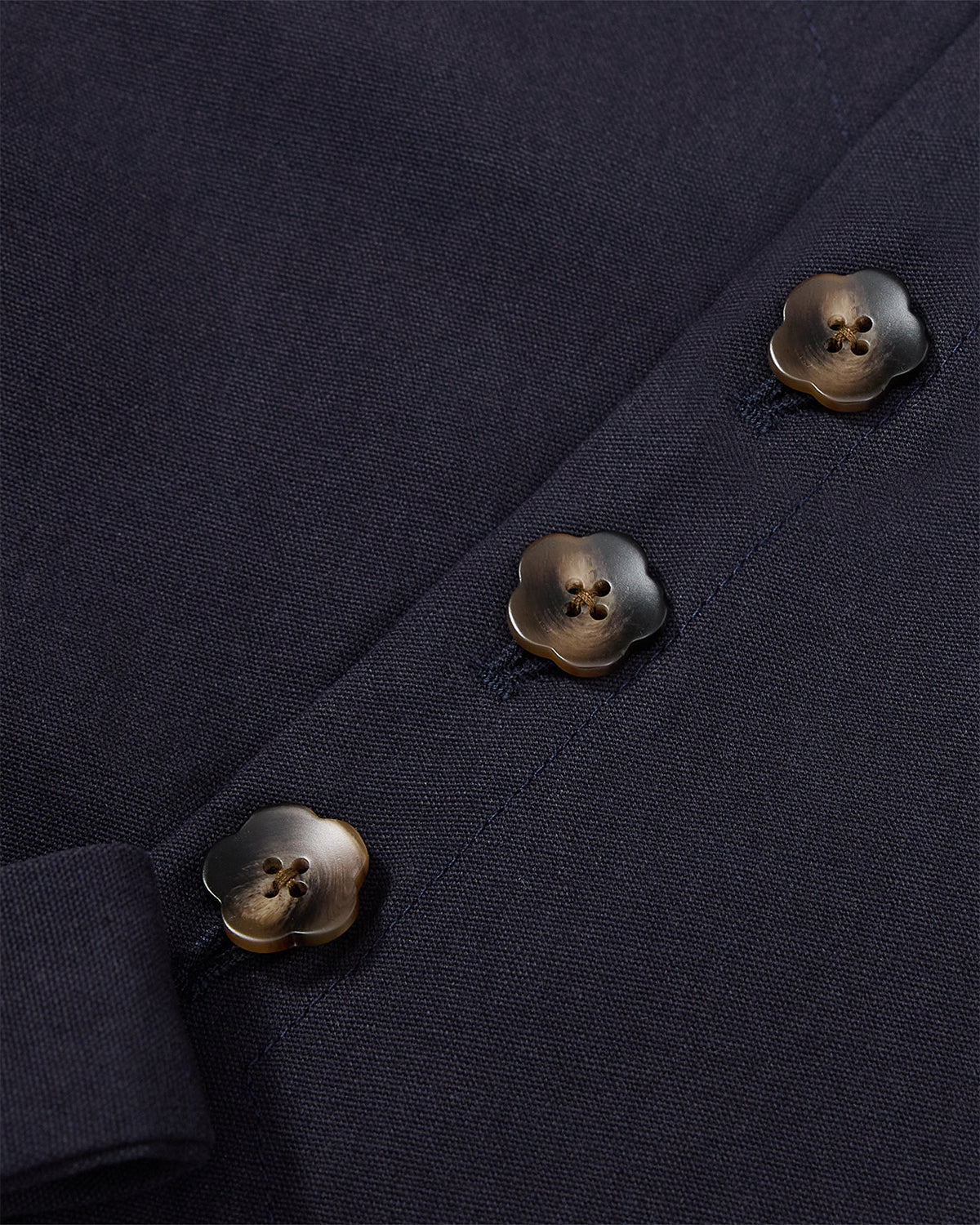 Detail view of three flower-shaped metallic buttons positioned asymmetrically on the front of the Hanbok Tie Blazer.
