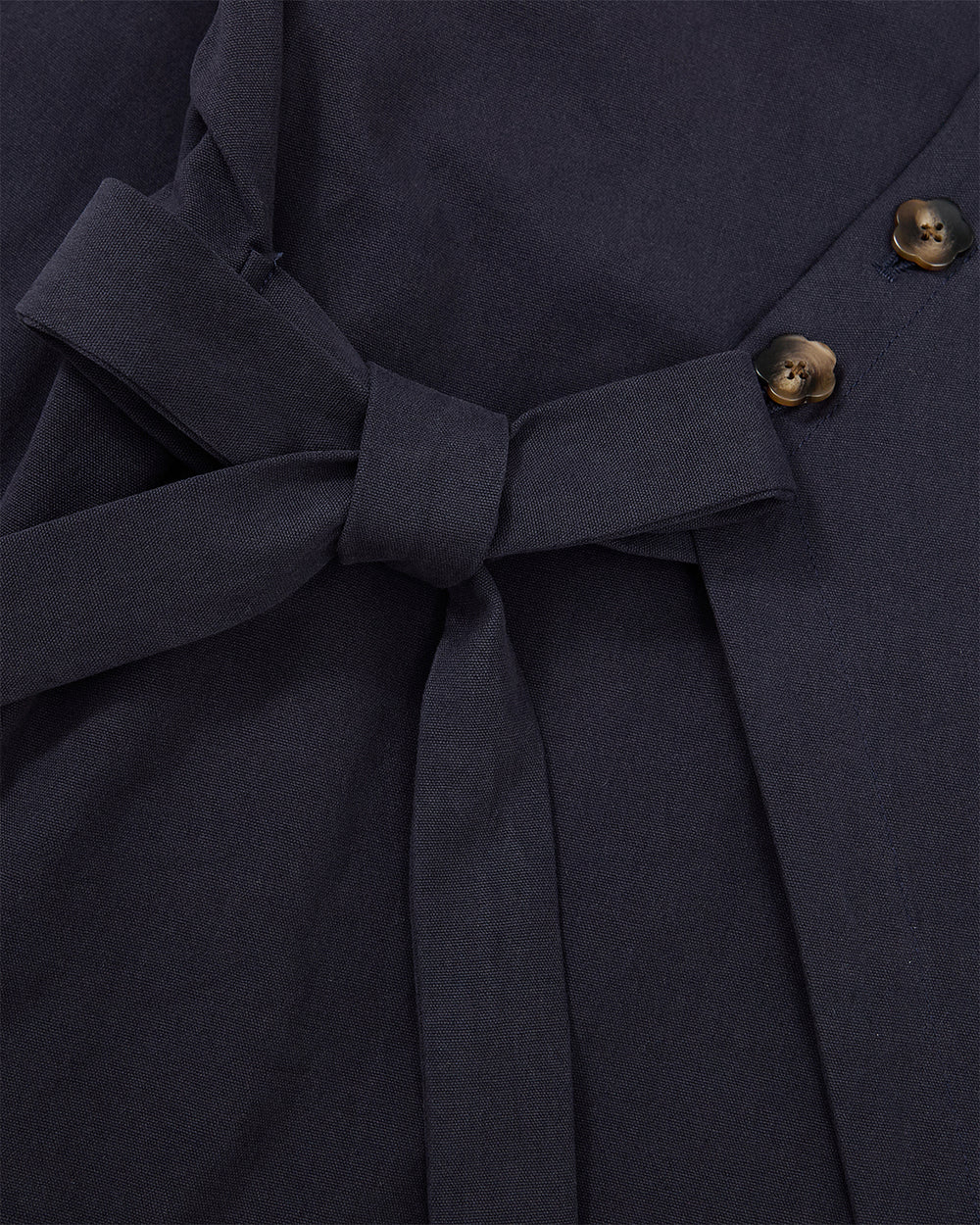 Close-up of Sundae School’s NAVY HANBOK TIE BLAZER, crafted from dark navy 100% cotton fabric, featuring a side tie closure at the waist and two dark brown buttons on the right.