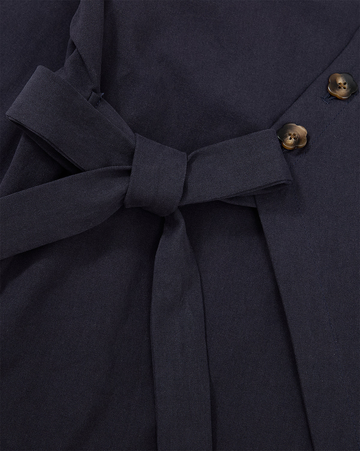 Close-up of Sundae School’s NAVY HANBOK TIE BLAZER, crafted from dark navy 100% cotton fabric, featuring a side tie closure at the waist and two dark brown buttons on the right.