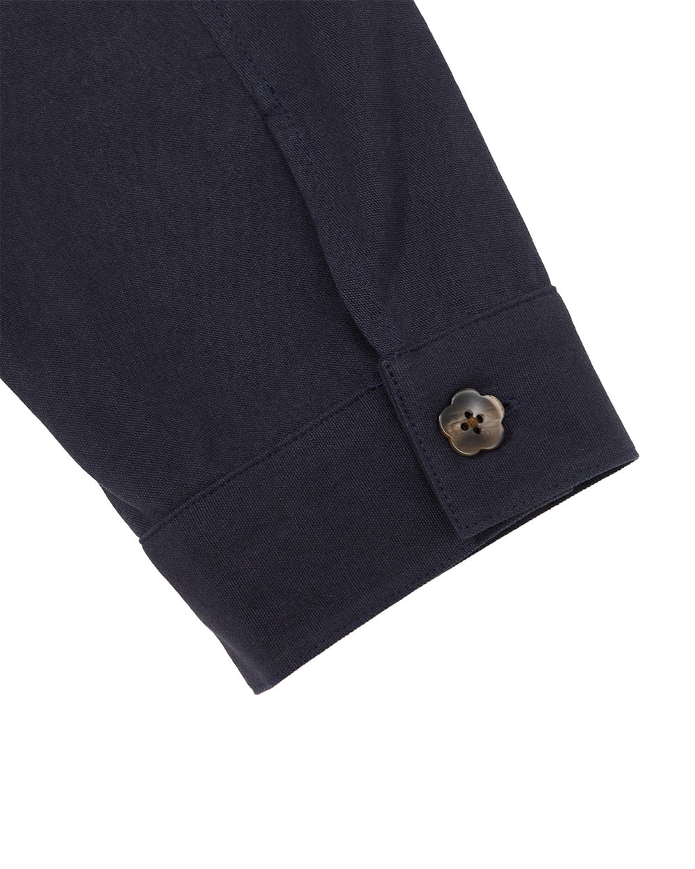 A close-up of the NAVY HANBOK TIE BLAZER by Sundae School showcases a dark navy cuff adorned with a distinctive flower-shaped brown button. Made from 100% cotton, the fabric looks smooth and expertly stitched, emphasizing the unique button detail.