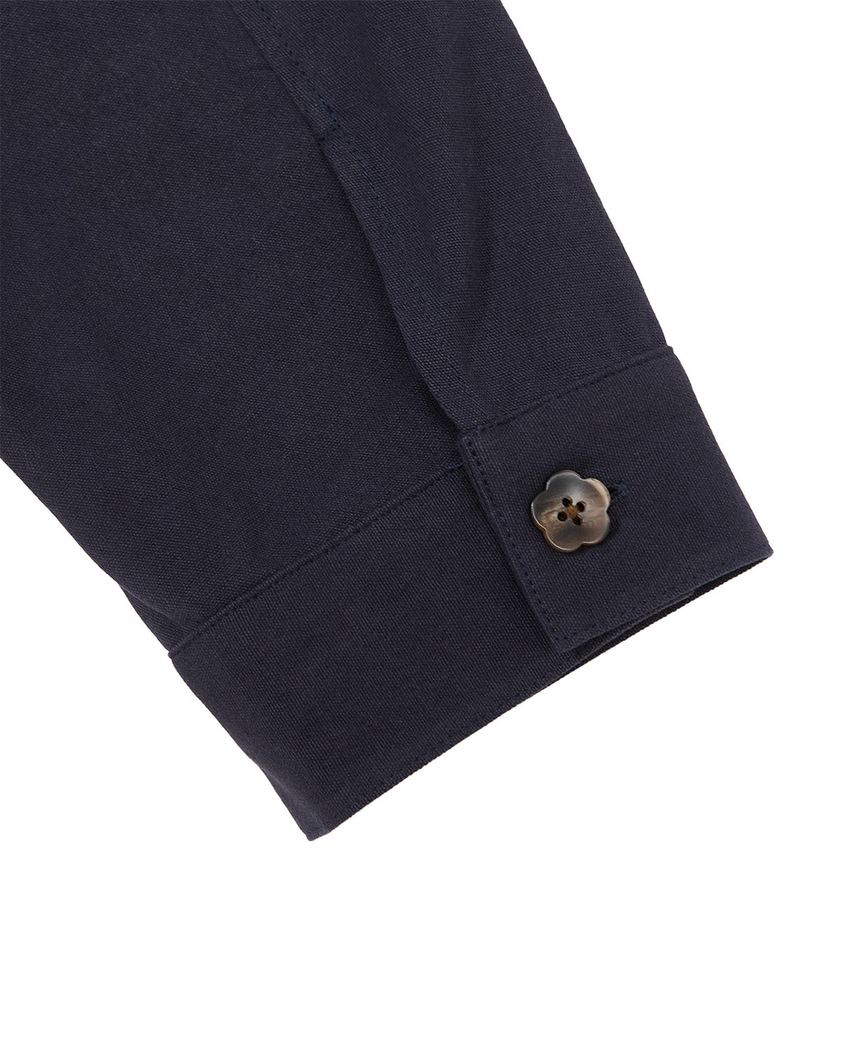 A close-up of the NAVY HANBOK TIE BLAZER by Sundae School showcases a dark navy cuff adorned with a distinctive flower-shaped brown button. Made from 100% cotton, the fabric looks smooth and expertly stitched, emphasizing the unique button detail.