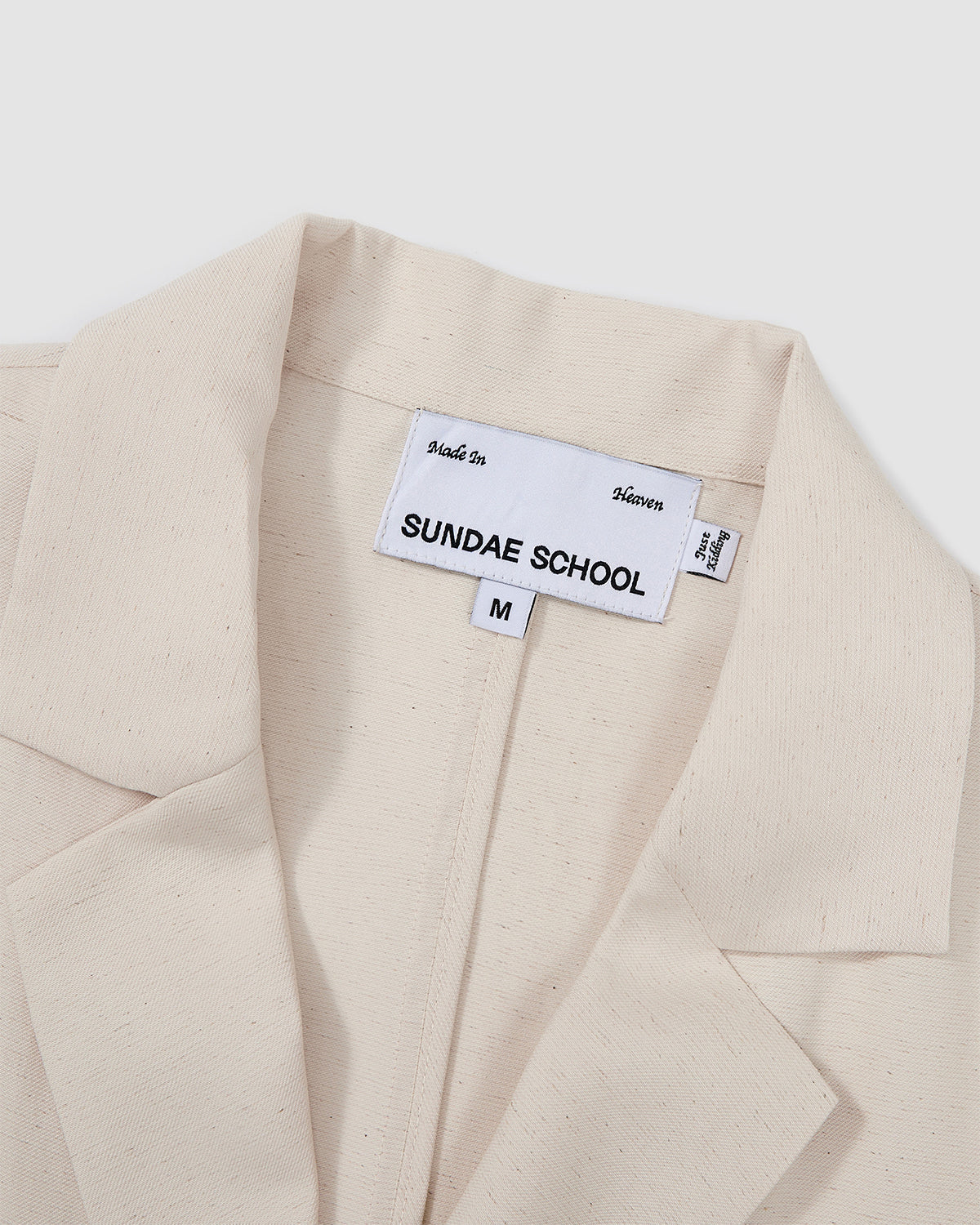Close-up detail of Sundae School cream hanbok shirt showing brand labels reading 