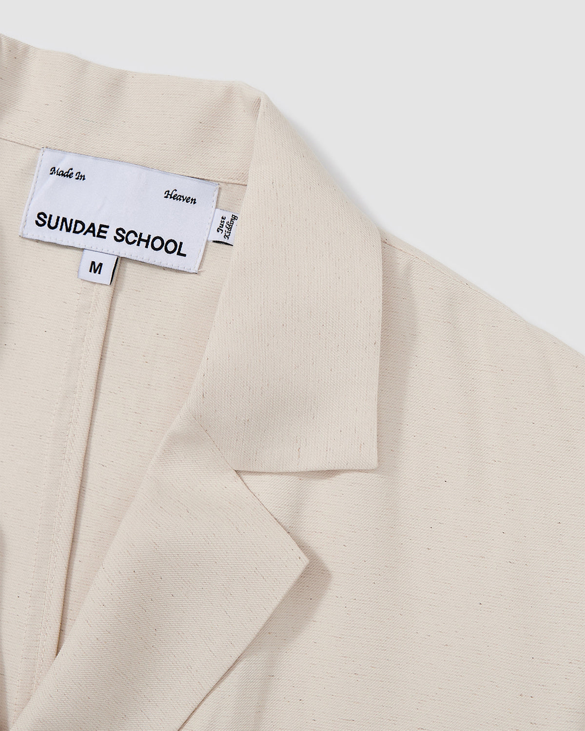 Close-up detail of cream hanbok shirt showing notched lapel and brand label placement with relaxed collar construction on textured linen blend fabric