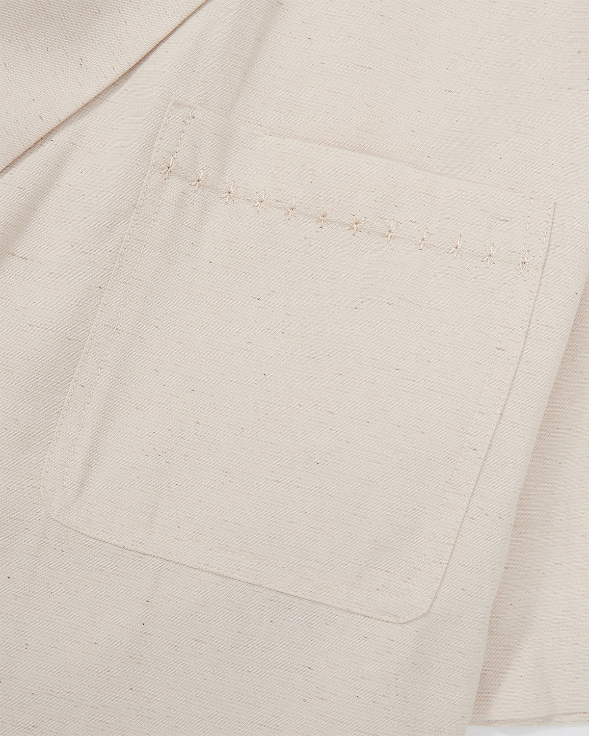 Close-up detail of cream hanbok shirt chest pocket showing decorative topstitching pattern in tonal thread on lightweight linen fabric