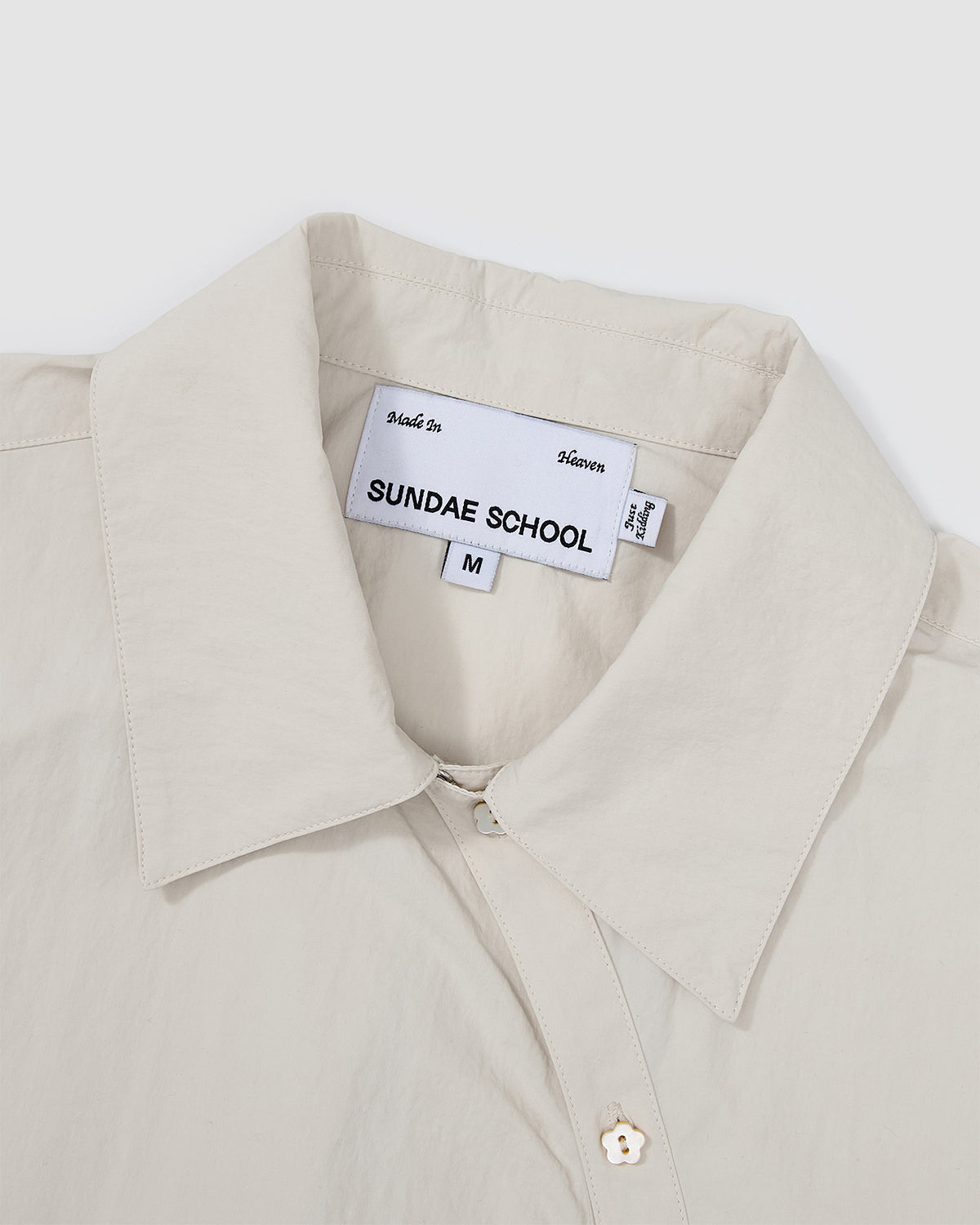 Close-up of the Ivory Yin Yang Short Sleeve Shirt collar area showing the Sundae School brand label and asymmetrical button closure.