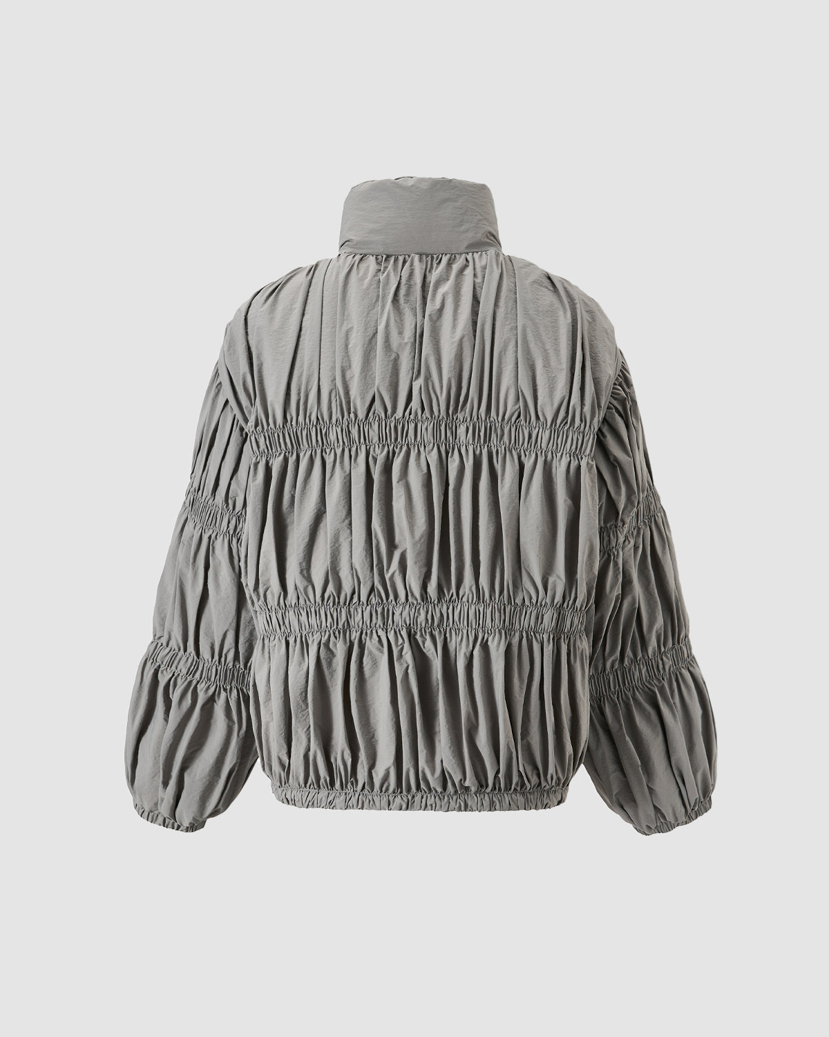 The Sundae School SMOKE PLEATED DUVET PUFFER is shown from the back, featuring gray pleated fabric with gathered horizontal ruching, a high collar, and elastic cuffs and hem for warmth.