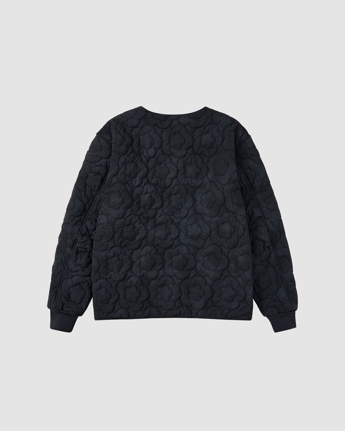 The BLACK MOCHI QUILTED MILITARY LINER by Sundae School, a black quilted long-sleeve sweatshirt with a subtle floral pattern, is displayed flat against a light gray background showing the back.