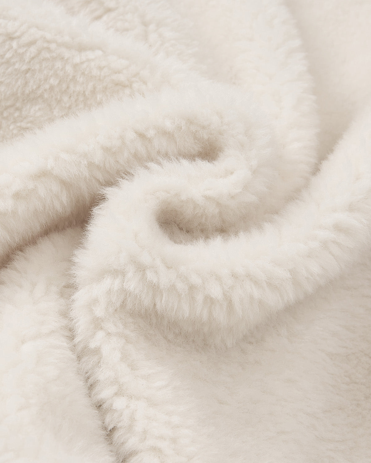 Close-up of plush, cream-colored sherpa fleece with a gentle swirl pattern from Sundae School’s BLACK IVORY REVERSIBLE FLOWER QUILTED JEOGORI FLEECE, highlighting its cozy texture and Korean-inspired jeogori jacket look.