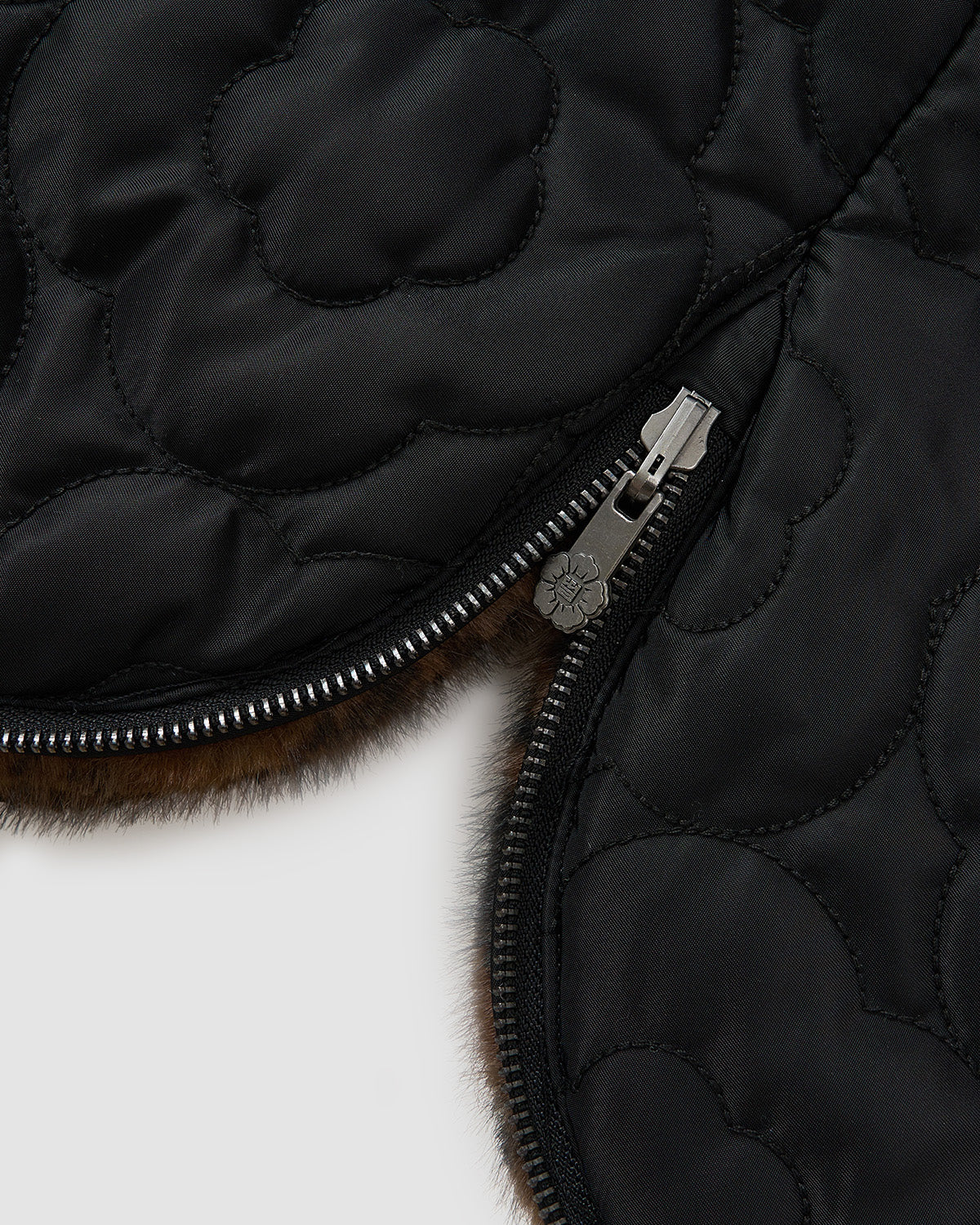 Close-up of Sundae School’s BLACK LEOPARD BAEJA VEST / BAG: black quilted fabric with a flower pattern, silver zipper partially open to show soft brown fur lining, inspired by the Korean baeja reversible vest.