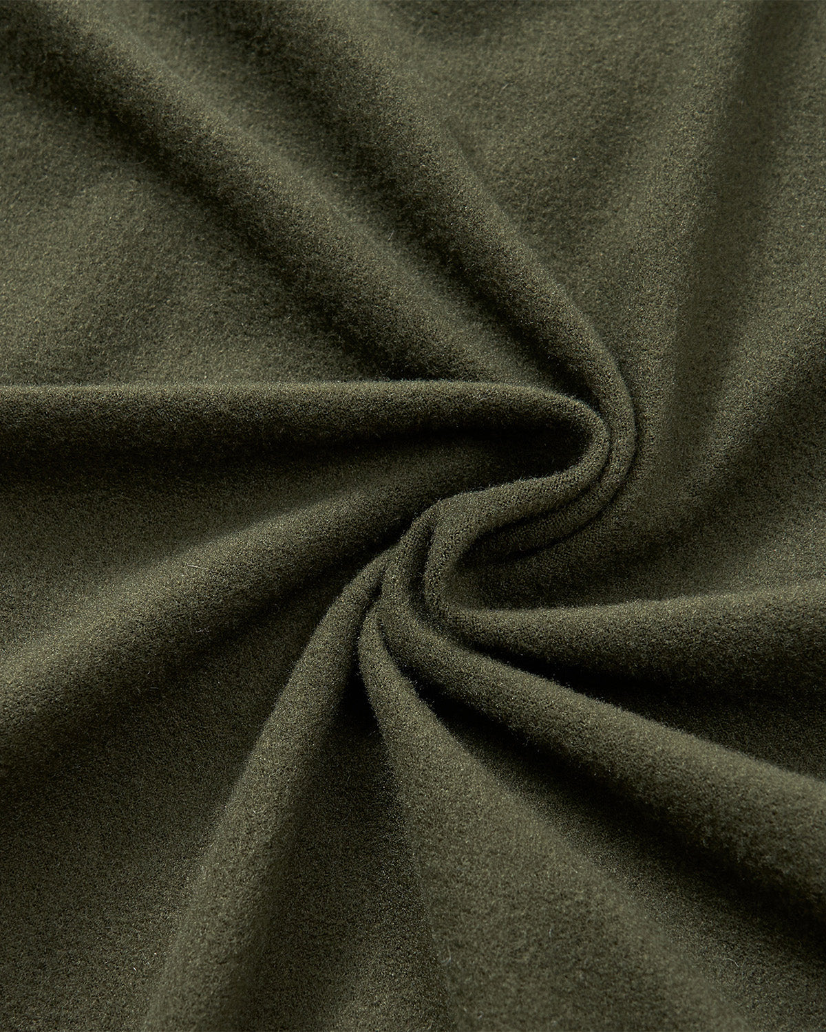 Close-up of olive green MATCHA MOCHI QUILTED MILITARY LINER fabric by Sundae School, featuring a soft, fuzzy texture with gentle folds and a swirling pattern gathered at the center.