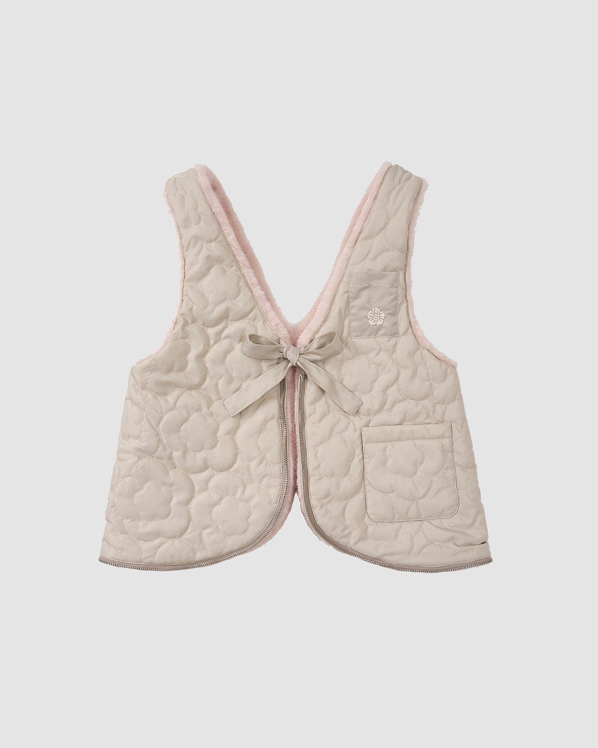 The Sundae School SILVER PINK BAEJA VEST / BAG is a light beige, quilted reversible vest with a floral pattern, pink inner lining, flower chest embroidery, front tie, side pocket, and is shown on a plain white background.