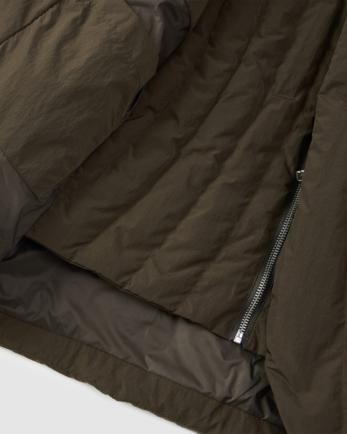 Close-up of the Sundae School KHAKI HEAVYWEIGHT MOCHI PUFFER in olive green, featuring insulated textured fabric, inner lining, and a partially open silver zipper for added warmth.