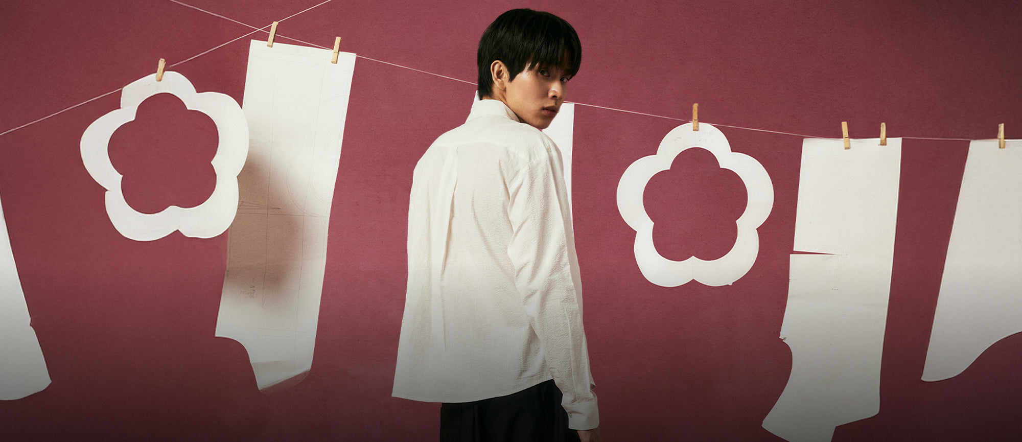 A male model wearing Sundae School Ivory Tie Gorum Shirt against a dark pink background 