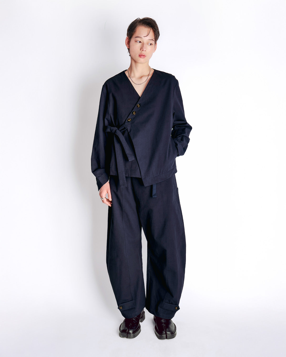 Model wearing the navy blue Hanbok Tie Blazer with matching wide-leg pants, styled with dark leather shoes and a delicate necklace.