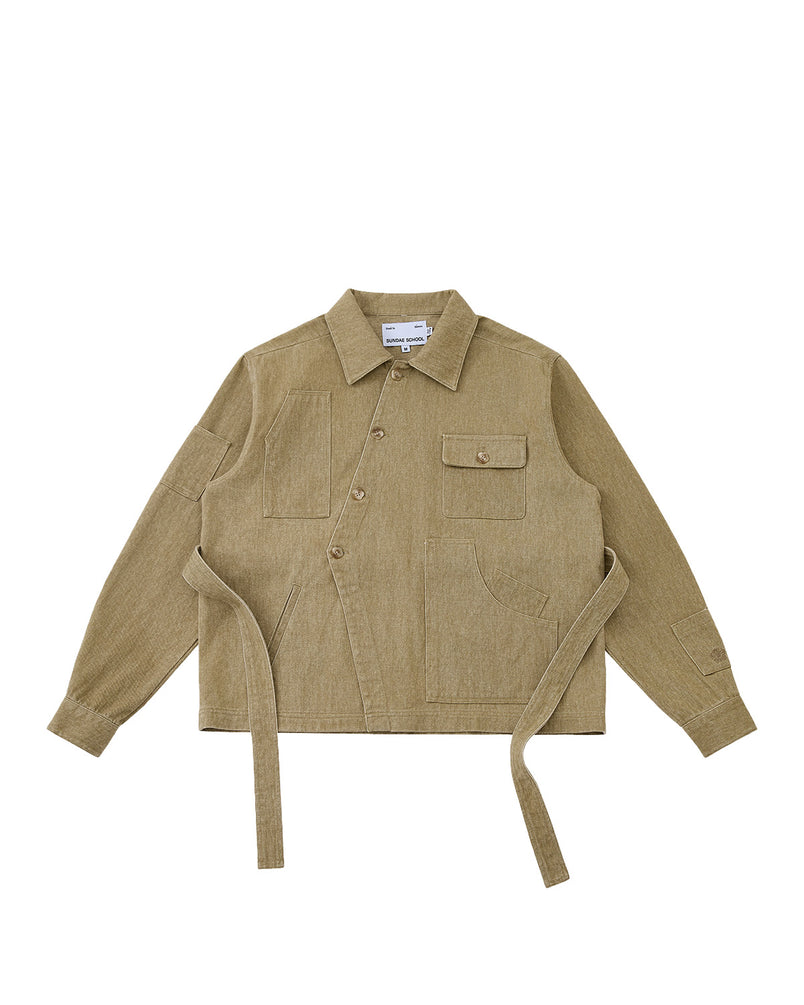 The TAN ASYMMETRIC WORK JACKET by Sundae School is a beige unisex jacket with a collar, front buttons, seven pockets, and two long side belts, shown on a plain white background.
