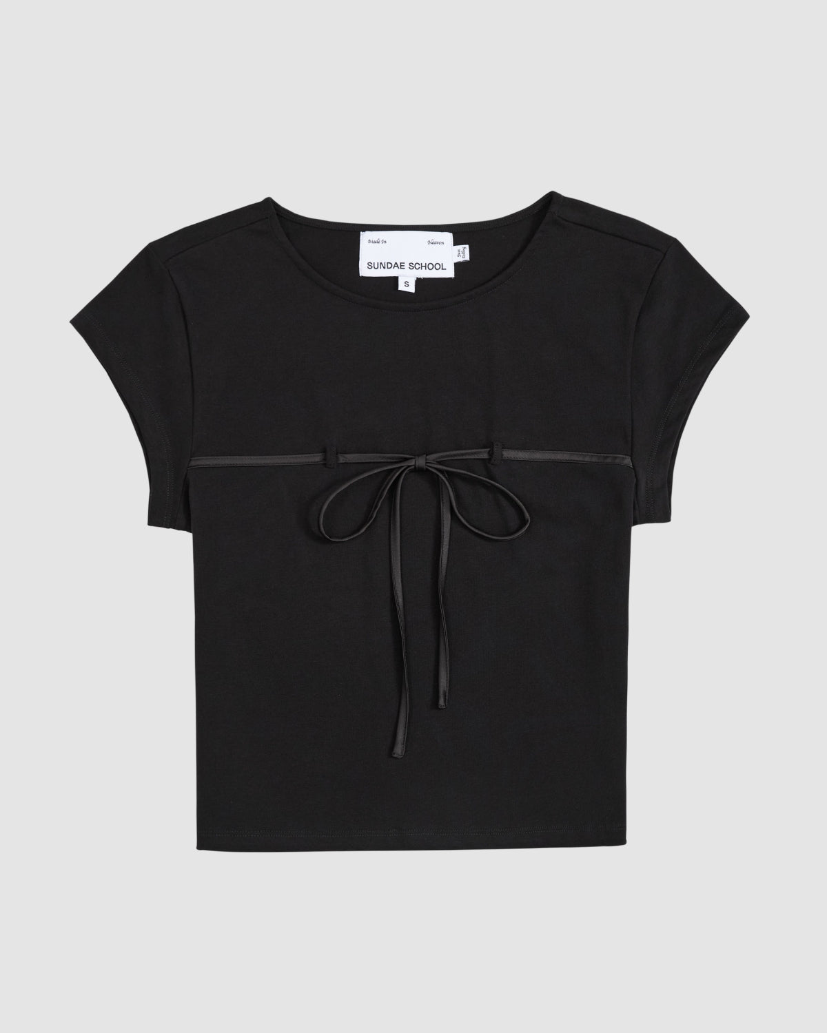 The BLACK TIE GORUM BABY TEE by Sundae School is a black, form-fitting women's top with short sleeves, a round neckline, and a thin ribbon bow across the chest. The background is light gray.