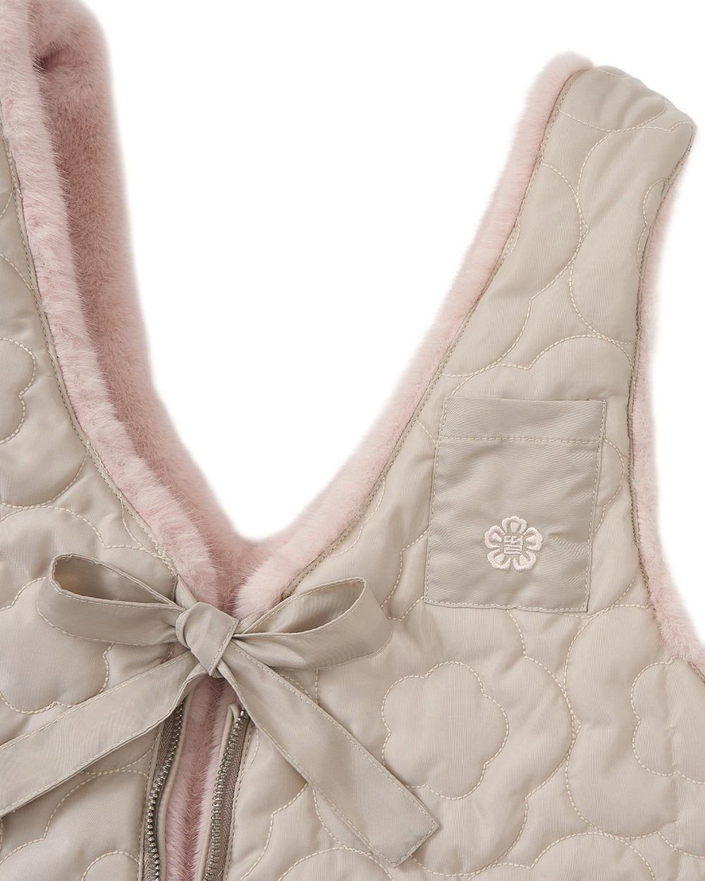 Close-up of the Sundae School SILVER PINK BAEJA VEST / BAG, featuring a quilted beige exterior adorned with a floral pattern, a small front pocket, pink fuzzy lining, and a beige ribbon tied in a bow near the zipper. This charming Korean-inspired vest is reversible for versatile styling.