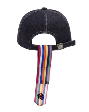 An INDIGO DAENGGI CAP by Sundae School in black denim, shown from the back with an adjustable fit and a rainbow-striped ribbon (daenggi) hanging from the strap, completed with a clover patch at the end of the ribbon. An embroidered Hangeul logo adds a distinctive touch to this standout accessory.
