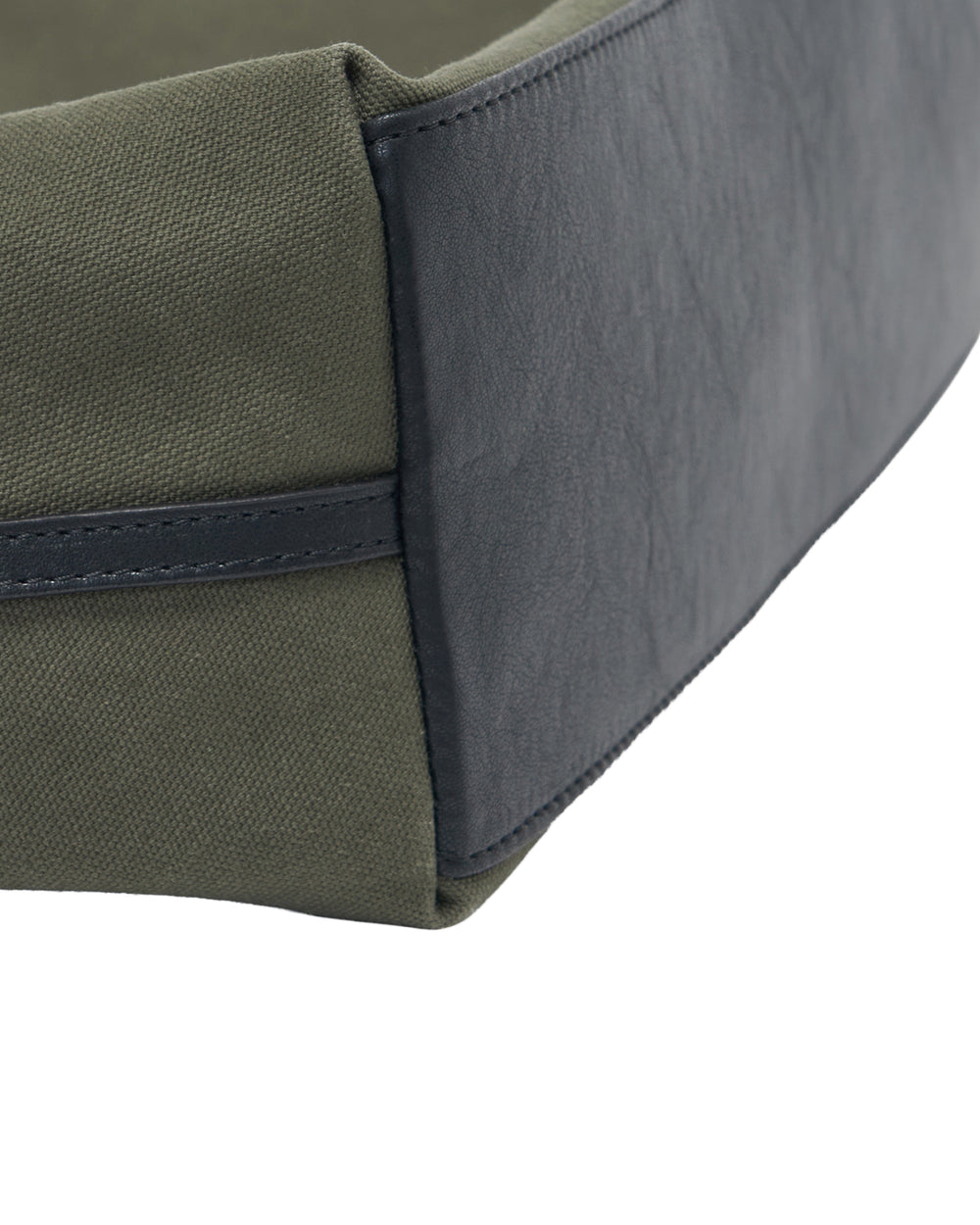 Close-up of the Sundae School OLIVE BOJAGI TIE TOTE BAG, featuring green canvas sides reminiscent of a cotton canvas bag and a black faux leather corner with visible stitching.