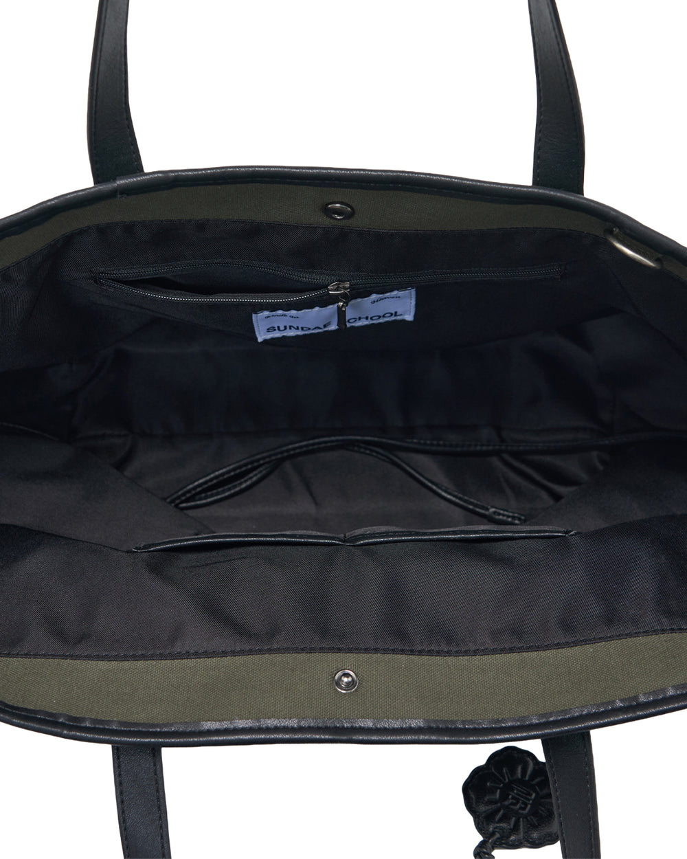 The OLIVE BOJAGI TIE TOTE BAG by Sundae School is shown open in black vegan leather, revealing a spacious interior with fabric lining, a zippered pocket, and a visible label inside. The bag features two handles and a top metal snap closure.