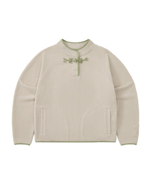 The TAUPE BUTTERFLY FLEECE PULLOVER by Sundae School is a cream-colored mock-neck polar fleece pullover with green trim, featuring a round collar adorned with hand-tied flower knots and decorative tteokbokki toggles at the neck, two front pockets, and long sleeves.