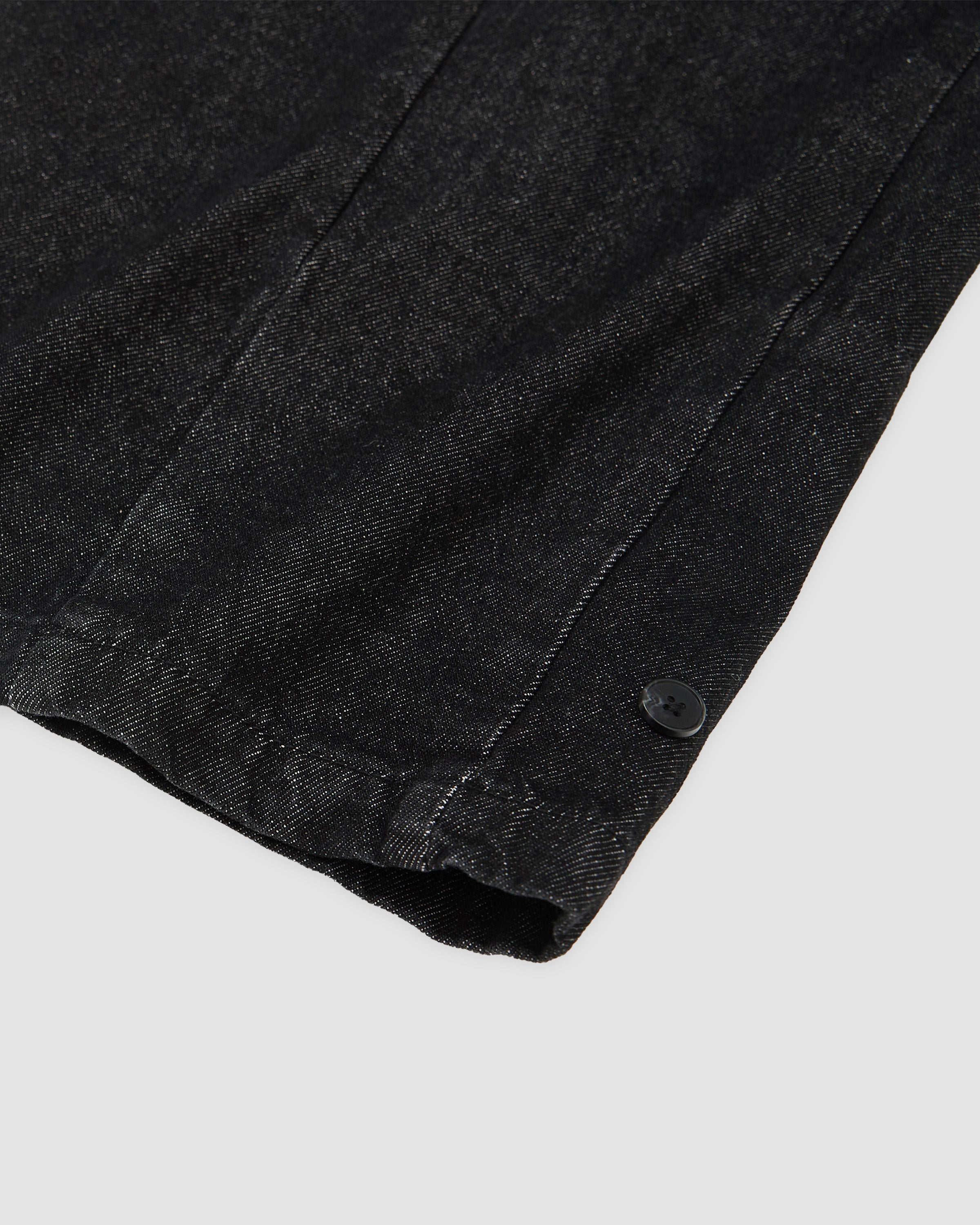 Close-up detail of black hanbok denim ankle cuff with black snap button closure, showing gathered elastic hem construction and denim texture details