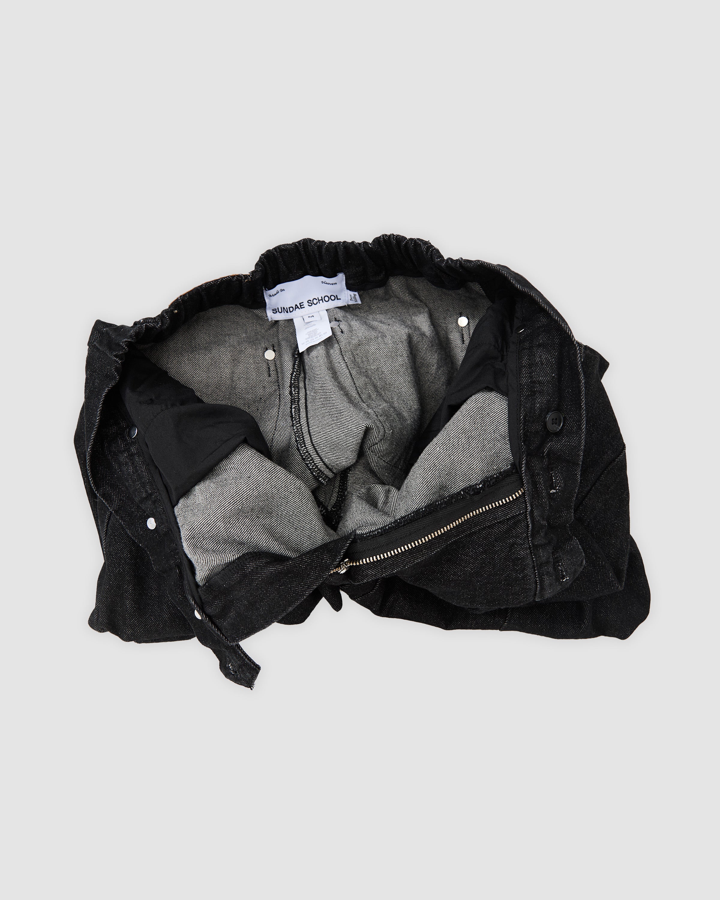 Sundae School black hanbok denim pants shown inside-out as flat lay, displaying internal construction with elastic waistband, gray cotton lining, size M label, and seam finishing details
