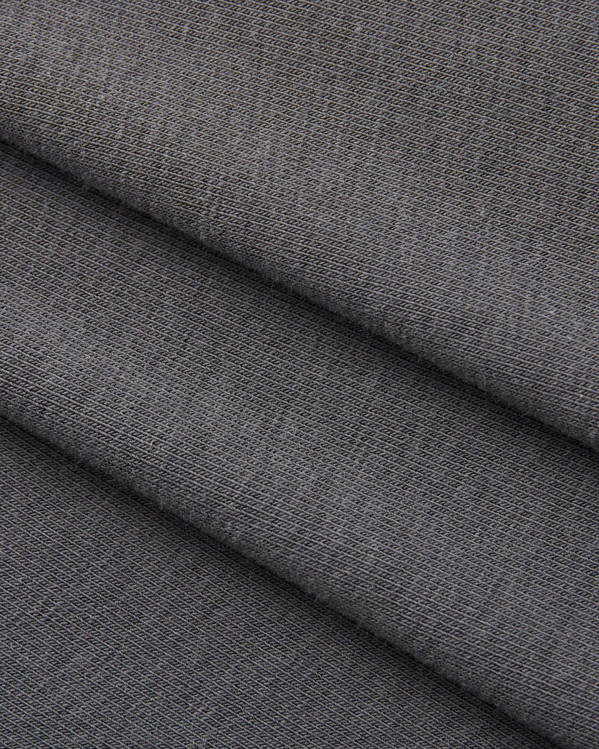 Close-up of folded DARK GREY CINDY POLO DRESS by Sundae School, highlighting its soft, smooth knit texture and fine pattern with subtle shadows from the overlapping folds—an ideal choice for crafting a sophisticated summer wrap dress with a fitted midi silhouette.