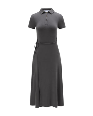The Sundae School DARK GREY CINDY POLO DRESS is a short-sleeve, dark gray collared midi dress featuring a buttoned neckline and a waist tie on the left side. With its gently flared skirt and fitted silhouette, this knee-length dress is shown against a white background.