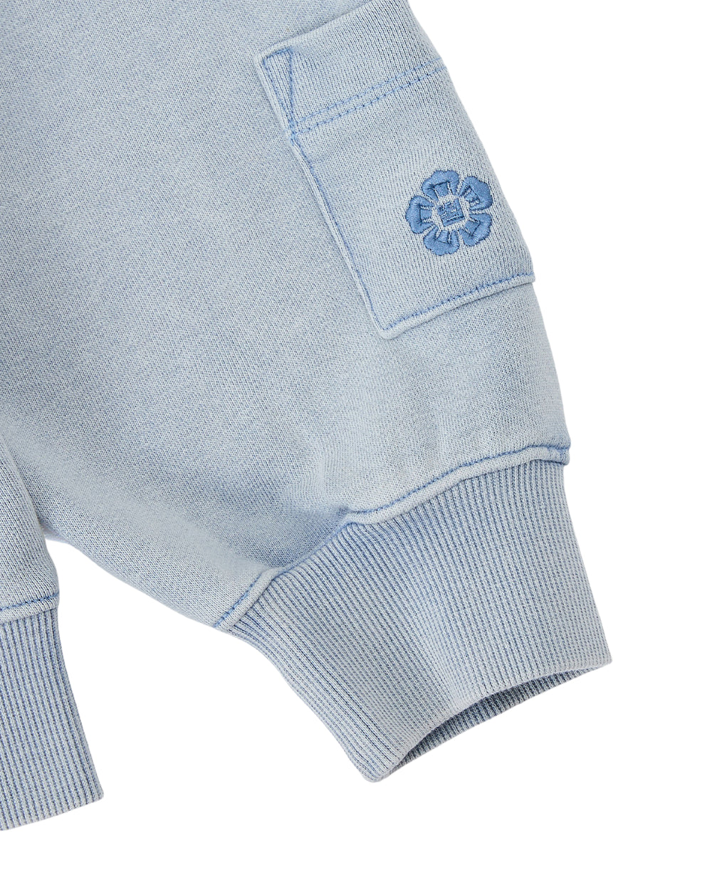 Introducing the SKY BLUE COCOON HOODIE by Sundae School—a soft knit piece in light blue, featuring ribbed cuffs, a small pocket adorned with an embroidered blue flower, and elegantly draped peret sleeves that create a subtle winged silhouette.