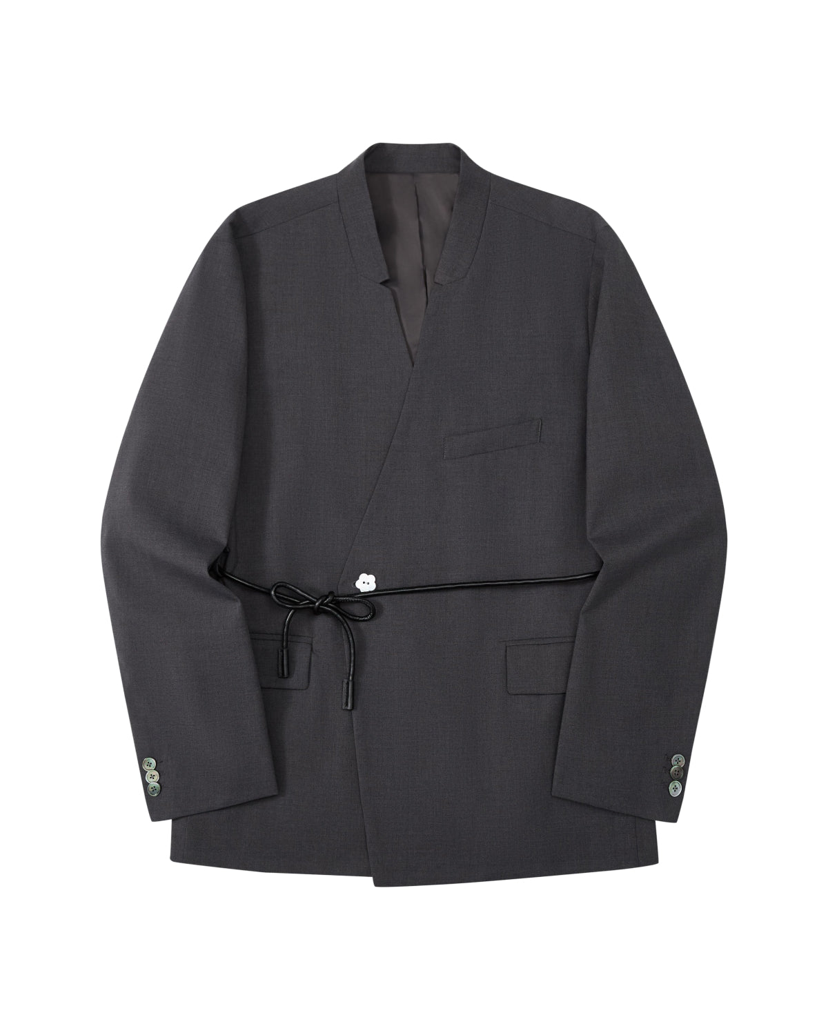 The COLLARLESS TIE BLAZER by Sundae School is a dark gray blazer with an unstructured drape and a shawl collar, designed without buttons. It features a single chest pocket, two front flap pockets, and comes with a thin vegan leather belt that ties at the waist.