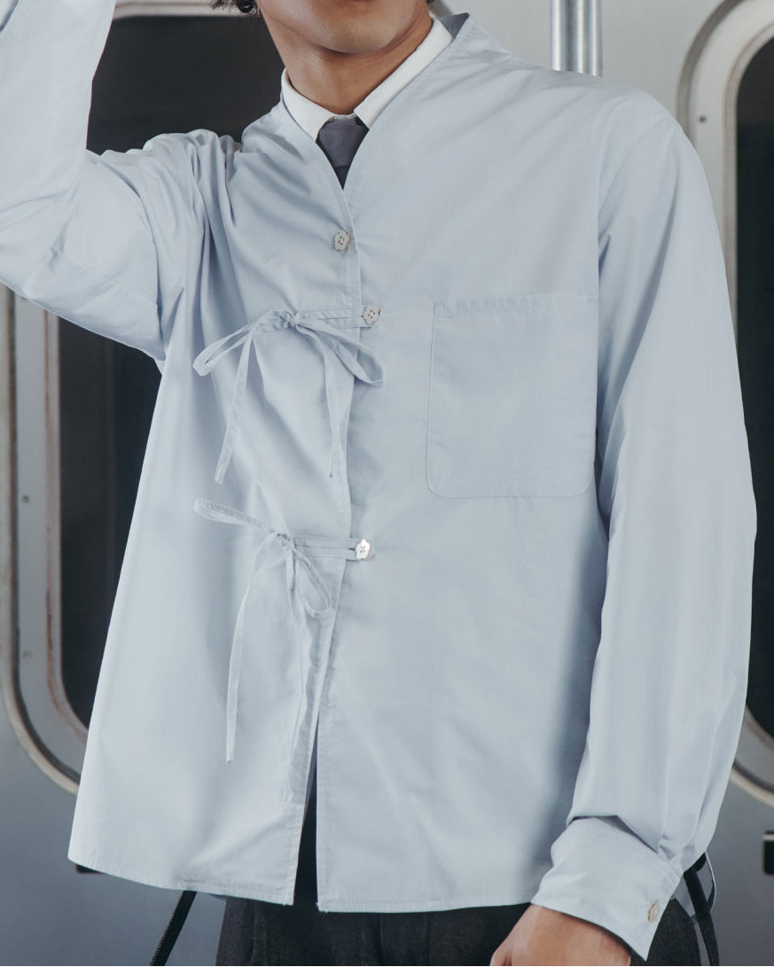 A young man wearing the Sundae School DART COLLAR SHIRT stands in a subway car, holding onto his hat. A subway map and seats are visible in the background.