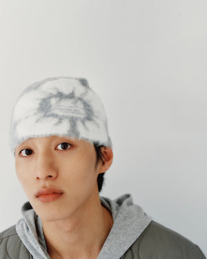 A person wearing a grey and white tie-dye GREY DDUL BEANIE as protective headgear and a grey hoodie.