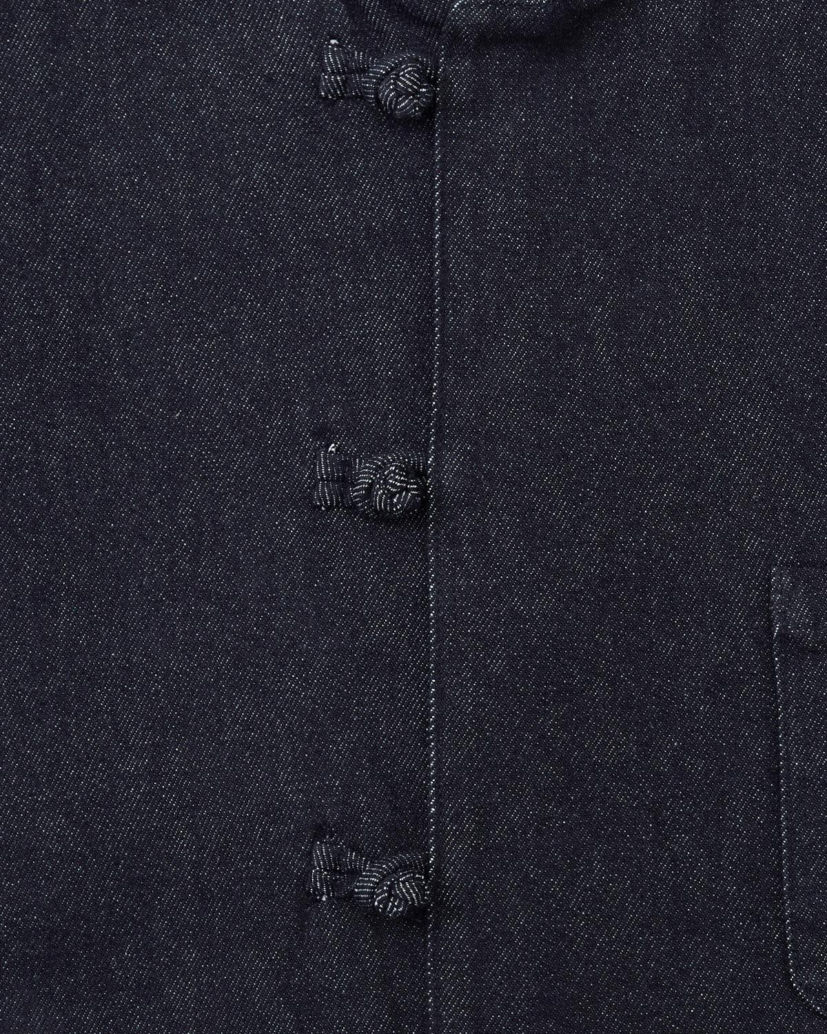 Close-up of the DENIM CHORE JACKET by Sundae School, showcasing dark fabric, three traditional frog closures, visible stitching, and a partial pocket on the right side.