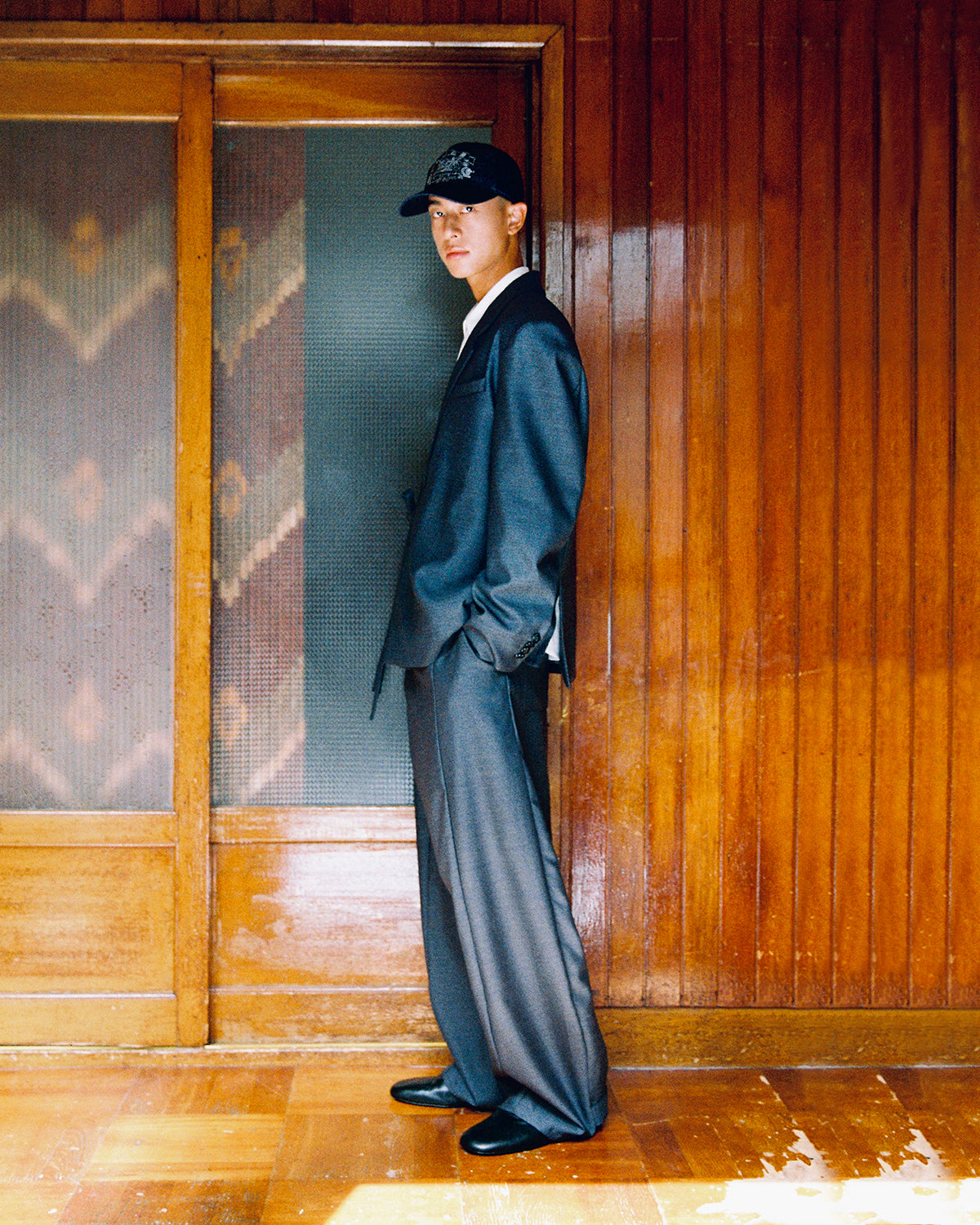 Side profile of a model in the Sundae School CHARCOAL DOUBLE DUTY BLAZER and CHARCOAL PLEATED HANBOK SLACKS, hands in pockets.