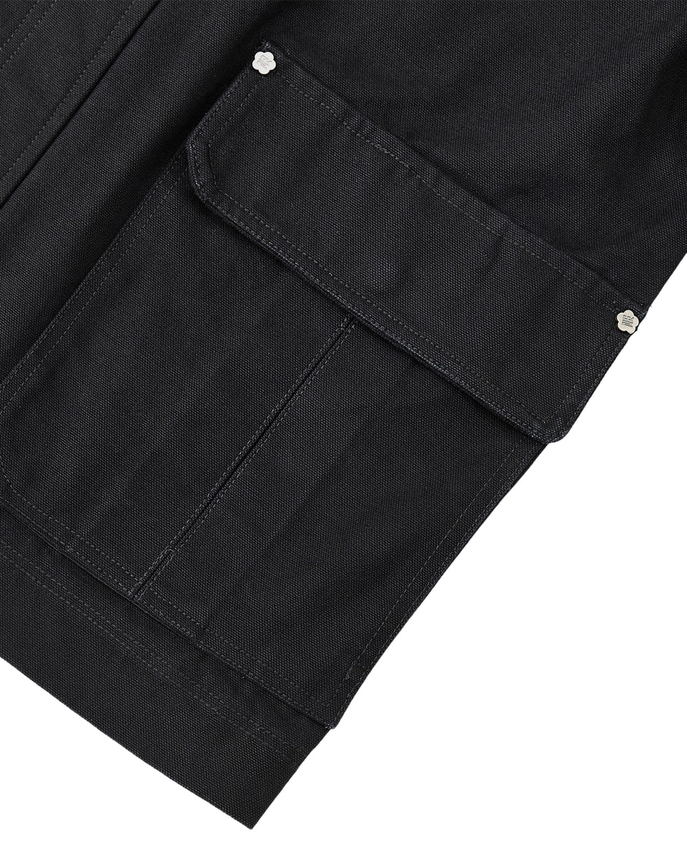Close-up of the BLACK FIREMAN CLASP JACKET by Sundae School, highlighting a black fabric workwear pocket with a flap and silver snap buttons on the corners, featuring custom Mochi Floral clasps. The image showcases detailed stitching and part of the garment’s edge for a touch of vintage effect.